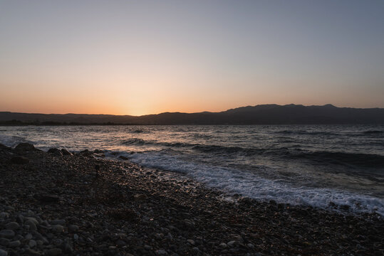 Sea panorama at sunset with waves washing over the stony beach shore