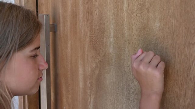 A girl knocks on a wooden door,
