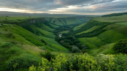 Obraz premium Expansive Green Valley with Winding River Under Cloudy Sky, Majestic Landscape Vista