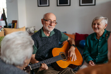 Senior man playing guitar in retirement home.