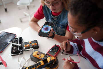 High school students working on robotics project, using online AI app to answer questions.