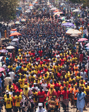 Bauchi, Nigeria - 31 March 2025: View of a vibrant procession through the city, a sea of colorful attires under the sun, with figures on horseback amidst the bustling crowd.