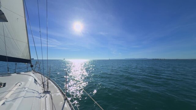 Valencia sailboat sailing on Mediterranean Sea with sun reflections