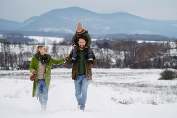 Father, mother and young son on walk in winter nature.