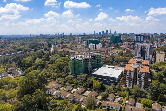 Aerial view of densely packed buildings nestled amidst a sea of green trees, with distant skyscrapers punctuating the horizon, Nairobi, Kileleshwa, Kenya.