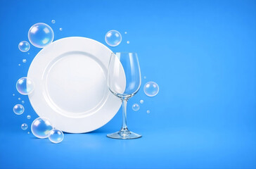 Clean dishes and sparkling glassware on a blue background. Dishwashing concept with copy space.