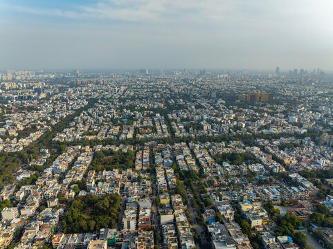 Aerial view of a sprawling cityscape with dense buildings and green spaces, as seen from Sector 15B Delhi - Jaipur Expressway, Gurugram, Haryana, India.