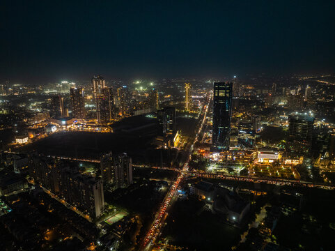 Aerial view of a sprawling cityscape illuminated by golden lights cutting through the dark, featuring Sector 15B on the Delhi-Jaipur Expressway, Gurugram, Haryana, India.