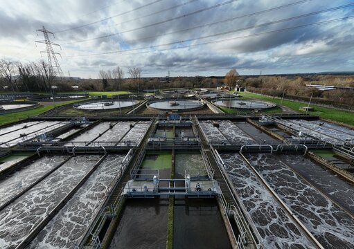 Aerial view of rectilinear and circular water treatment pools contrast sharply against the backdrop of Hoddesdon's industrial landscape, Hoddesdon, United Kingdom.