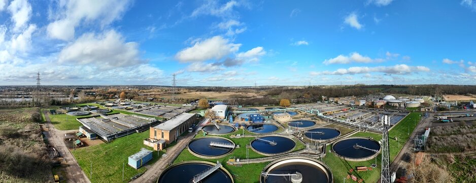 Aerial view of the intricate network of circular tanks and rectangular structures, a symphony of industrial design against a backdrop of green fields, Hoddesdon, United Kingdom.