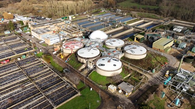 Aerial view of the sewage works, where circular tanks contrast with the surrounding greenery, creating a stark industrial landscape, Hoddesdon, United Kingdom.