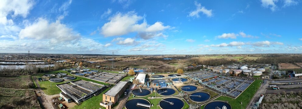 Aerial view of circular tanks contrast against the green landscape under a sky streaked with white clouds, Hoddesdon, United Kingdom.