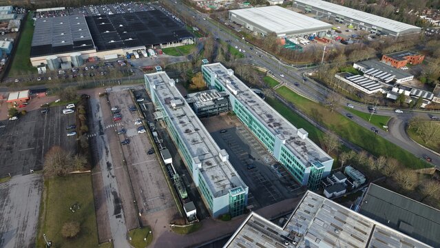Aerial view of modern buildings casting long shadows next to a bustling highway, contrasting with the bare trees surrounding The Offer Hub, Stevenage, United Kingdom.