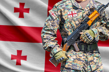 Naklejka premium Georgia flag with soldier in military uniform holding assault rifle in front of it
