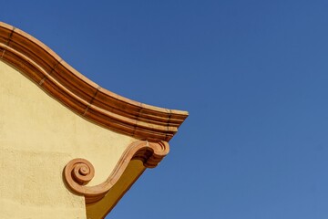 Detail of a roof with ornamental shapes on a blue sky background. © Manuel