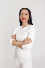 Fototapeta premium Confident Brunette Woman in White Sportswear Posing with Folded Arms and Bright Smile