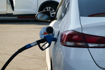 Gas station. Part of a car with a fuel nozzle inserted into the gas tank. Close-up.