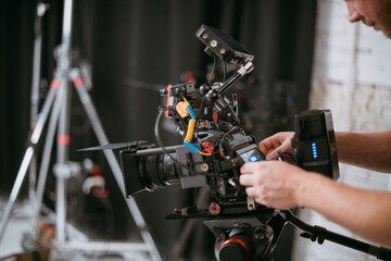 Fototapeta premium Professional cinema and video camera on the set. Shooting shift, lighting fixtures, shooting equipment and the team. Technique of modern filming and advertising.