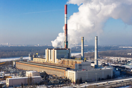 Aerial view of coal power plant releasing white exhaust gas from smoke stacks, representing industrial energy production and pollution, Warszawa, Wojewodztwo mazowieckie, Poland.