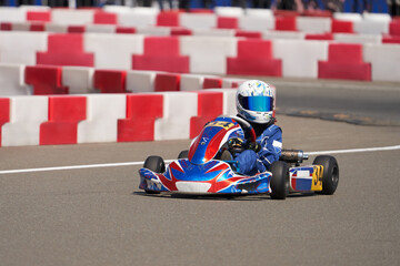 A child in a small-displacement racing car on a track with turns. Children's karting.