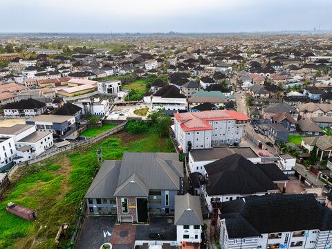 Aerial view of rooftops and buildings contrasting with green spaces under a cloudy sky, Ede Okia Community Road, Port Harcourt, Rivers, Nigeria.