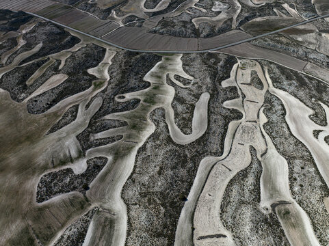 Aerial view of the arid land, with its intricate patterns carved by erosion, creates a stark, textured landscape of contrasting light and shadow, Villamayor de Gallego, Zaragoza, Spain.