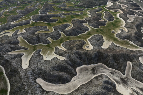 Aerial view of winding patterns etched into the landscape, contrasting starkly with the muted earth tones, Villamayor de Gallego, Zaragoza, Spain.