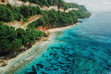 Fototapeta premium Beach under cliffs with quiet ocean in Bali. Aerial view