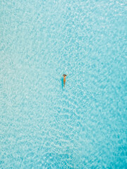 Woman floating in crystal clear water, summer vacation scene. Above view
