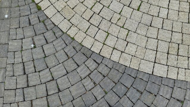 shot of curved cobblestone paving featuring contrasting light grey and dark charcoal granite blocks