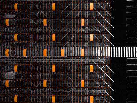 Aerial view of the dark, geometric patterns of stacked materials contrasted by bright orange accents and stark white lines, Warszawa, Wojewodztwo mazowieckie, Poland.