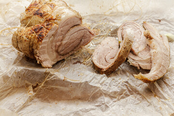 Sliced homemade meat loaf or roll on crumpled parchment paper. Rustic roasted pork dish texture.