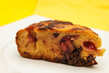 Slice of homemade cherry pie or cake on a white plate against a yellow background. Sweet berry dessert.