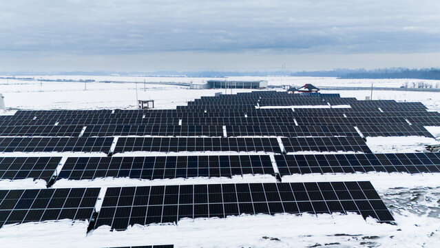 Aerial view of solar panels contrasting against the stark white snow-covered landscape under a muted sky, capturing the essence of winter's embrace, Sremska Mitrovica, Vojvodina, Serbia.