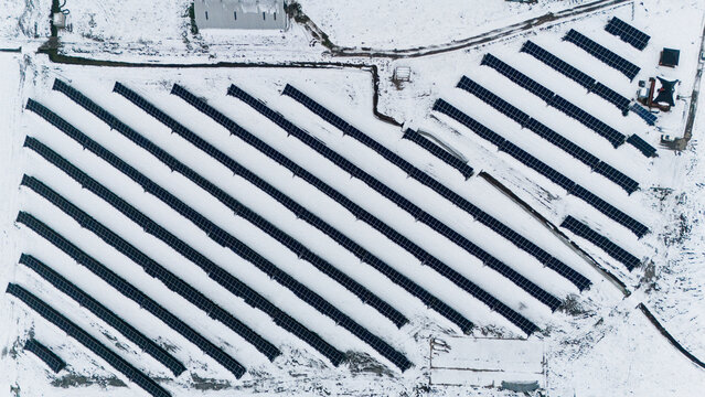 Aerial view of solar panels arrayed in snowy fields, stark lines cutting through the white landscape, Sremska Mitrovica, Vojvodina, Serbia.