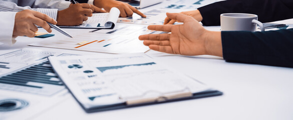 A diverse group of professionals engages in a dynamic meeting, analyzing charts and data on a...