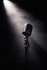 A vintage microphone bathed in a single spotlight against a dark backdrop, evoking a sense of anticipation and performance.