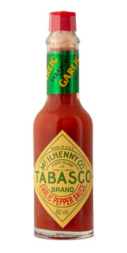 A glass bottle holds Tabasco brand garlic pepper sauce. The bottle features a green and yellow label with brand information. The cap is red. This sauce is often used to add flavor to dishes