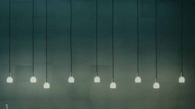 Minimalist pendant light bulbs creating a soft glow above a clean kitchen counter, featuring simple decorative objects and stacked dishes in a modern, uncluttered interior setting