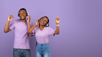 Favourite Playlist. Portrait of excited young black couple wearing wireless headphones and dancing....