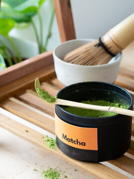 Matcha powder in container with bamboo scoop