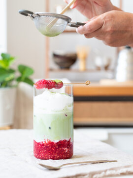 Preparing iced raspberry matcha latte with frothy foam