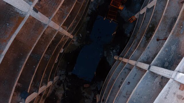 Going down inside the atrium in the building under construction. Approaching the bottom of the structure with a large puddle.