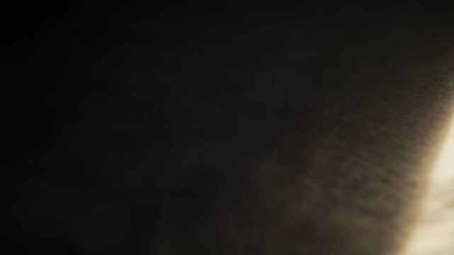 Warm sunlight streams through a window, casting strong parallel lines and creating an abstract pattern of light and shadow on a softly textured surface, evoking a serene and calm atmosphere