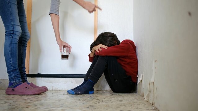 Child cowering in fear during parental verbal abuse and alcoholism, experiencing domestic violence, neglect, and trauma in a distressed home environment
