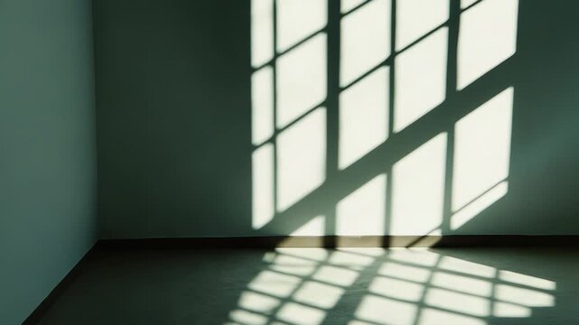 Geometric window shadows creating a grid pattern of natural light and dark areas on an empty room's corner wall and floor, showing abstract design and sunlight