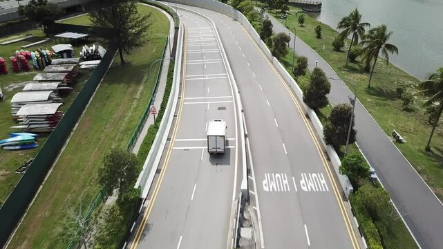 Drone shot of white van driving on road near Kallang river (Singapore)