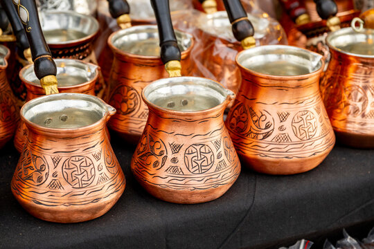 Metal coffee cezve with decorative oriental pattern on the shop window. Household items copper items for sale. Cupric coffeepots at the bazaar in Antalya Turkey. Turkish coffee pots. Metal coffee cezv