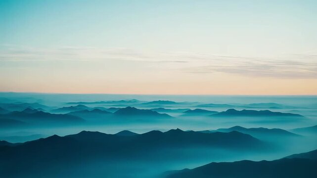 Layered mountains extend into the distant horizon, creating a serene and vast landscape with soft atmospheric haze blanketing the valleys between the peaks