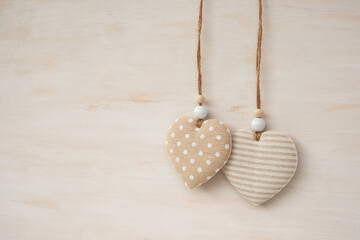 A pair of fabric hearts hanging against a wooden background